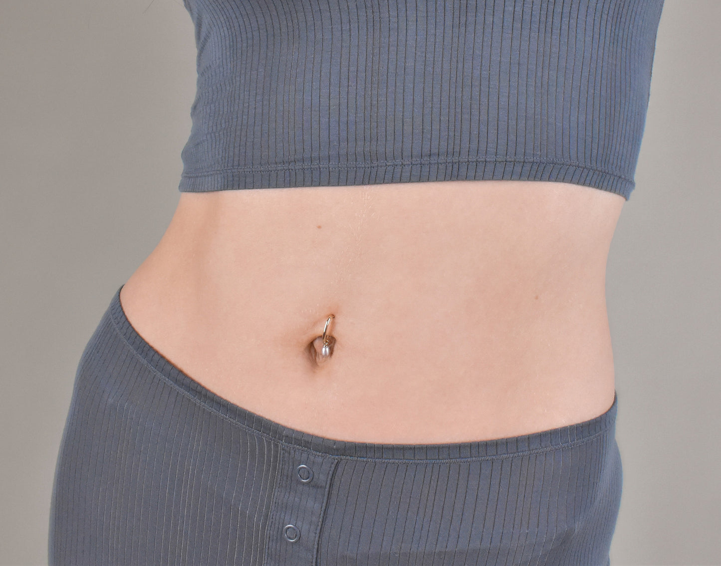 Gold belly ring with pearl charm in yellow gold.